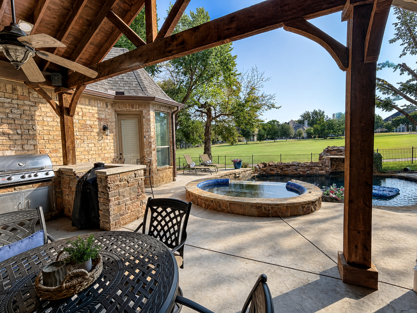Covered outdoor kitchen and seating area overlooking a pool at a Bound AV audio installation